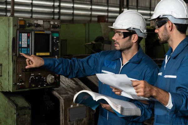 Group of skillful factory workers using machine equipment in workshop