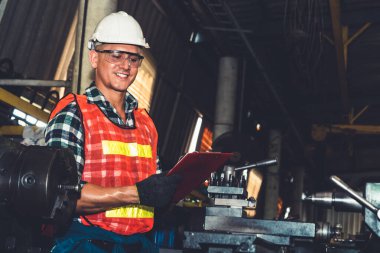 Akıllı fabrika işçisi veya mühendisi bir imalat atölyesinde makine işi yapıyor.