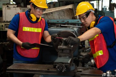 Bir grup yetenekli fabrika işçisi atölyede makine ekipmanı kullanıyor.