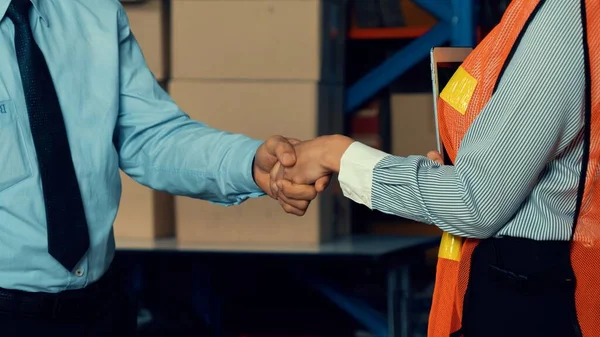 Warehouse worker handshake with manager in storehouse