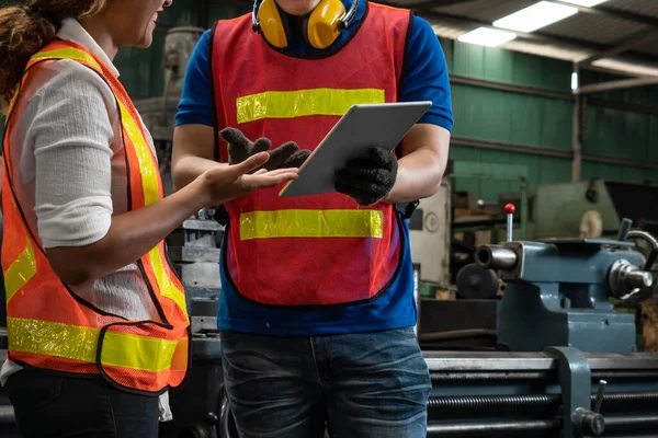 Two skillful factory engineer or worker discussing project on tablet computer