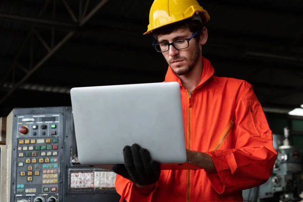 Geschickter Fabrikarbeiter, der mit Laptop arbeitet, um Prozeduren-Checkliste zu erstellen . — Stockfoto