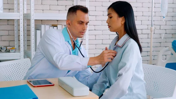 Doutor em uniforme profissional examinando paciente no hospital — Fotografia de Stock