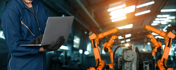 Engineer use advanced robotic software to control industry robot arm in factory