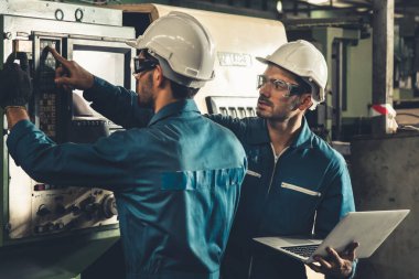 Bir grup yetenekli fabrika işçisi atölyede makine ekipmanı kullanıyor.