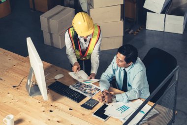 Depo müdürü ve işçisi depoda çalışıyor.