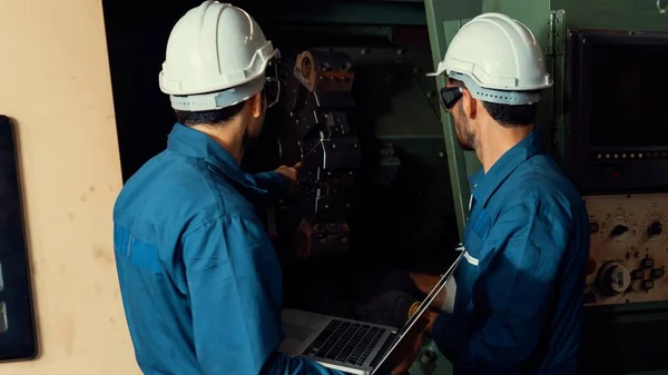 Group of skillful factory workers using machine equipment in workshop