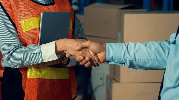 Warehouse worker handshake with manager in storehouse