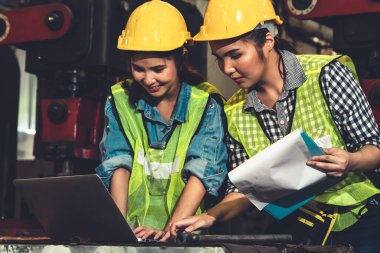 Fabrika işçileri fabrikada çalışıyor ve üretim planlarını tartışıyorlar.