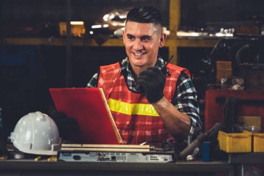 Fabrika işçisi, makine parçalarını incelerken taşınabilir radyodan konuşuyor.