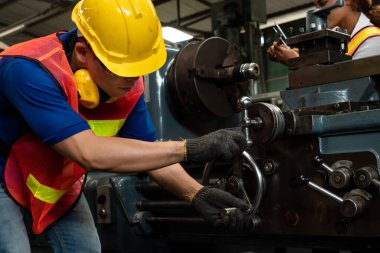 Bir grup yetenekli işçi fabrika atölyesinde makine teçhizatı kullanıyor.