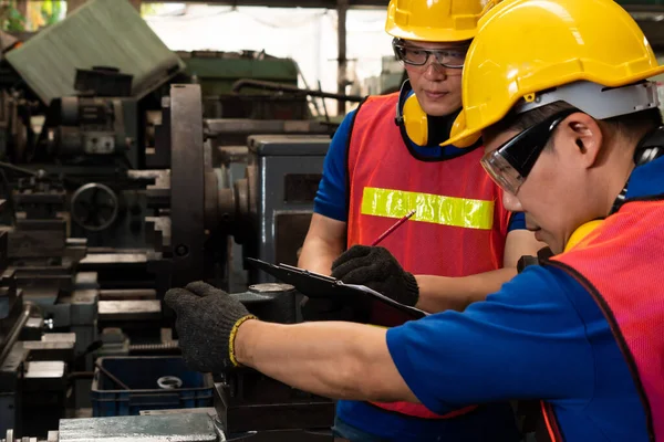 Groep bekwame fabrieksarbeiders die machineapparatuur gebruiken in de werkplaats — Stockfoto