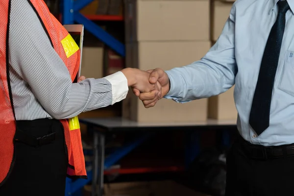 Warehouse worker handshake with manager in storehouse