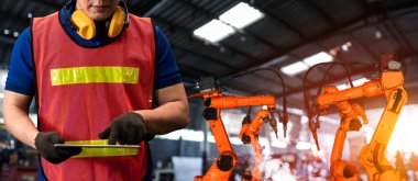 Mühendis fabrikadaki robot kolu kontrol etmek için gelişmiş robotik yazılım kullanıyor.