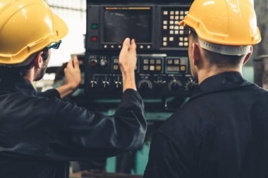 Bir grup yetenekli fabrika işçisi atölyede makine ekipmanı kullanıyor.