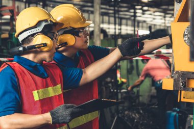 Bir grup yetenekli fabrika işçisi atölyede makine ekipmanı kullanıyor.