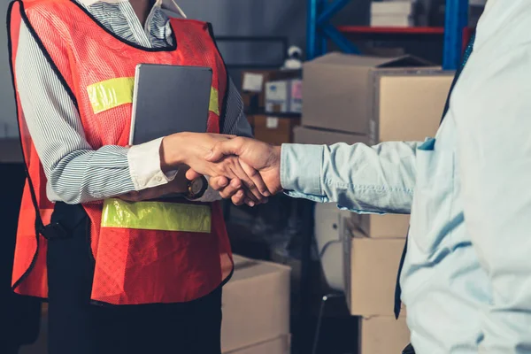 Warehouse worker handshake with manager in storehouse