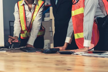 Depo müdürü ve işçisi depoda çalışıyor.