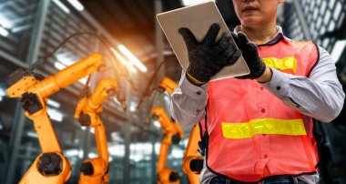 Mühendis fabrikadaki robot kolu kontrol etmek için gelişmiş robotik yazılım kullanıyor.