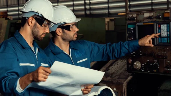 Group of skillful factory workers using machine equipment in workshop