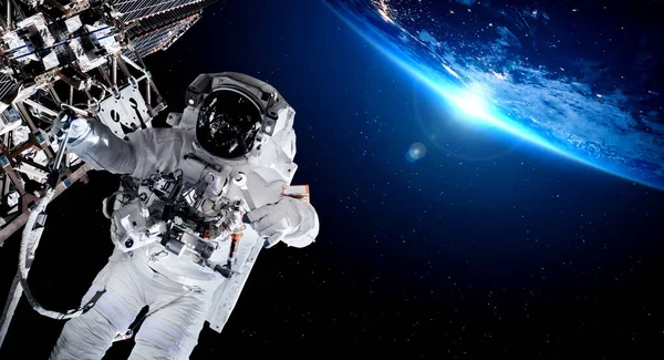 宇宙飛行士は宇宙ステーションで働いている間に宇宙遊泳をします — ストック写真