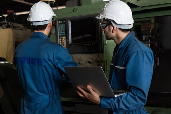 Group of skillful factory workers using machine equipment in workshop