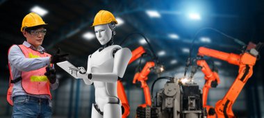 Mekanize endüstri robotu ve insan işçileri gelecekteki fabrikada birlikte çalışıyorlar.