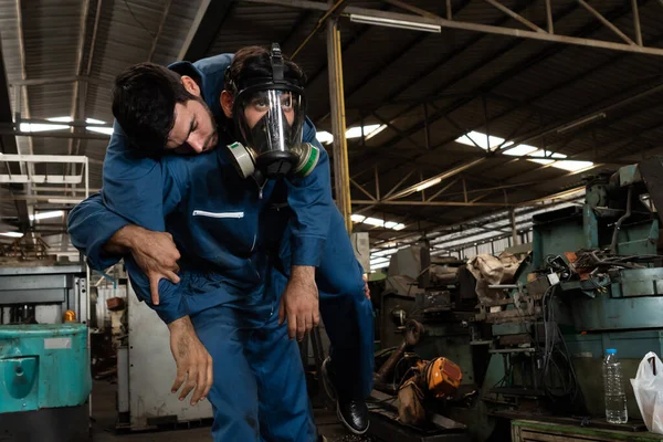 Umiejętny pracownik fabryki ratuje kolegę z drużyny przed wyciekiem trującego gazu. — Zdjęcie stockowe
