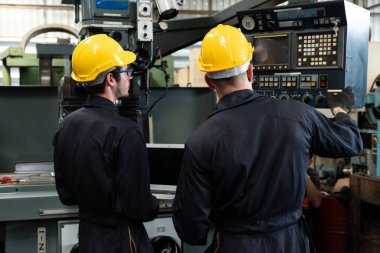 Bir grup yetenekli fabrika işçisi atölyede makine ekipmanı kullanıyor.