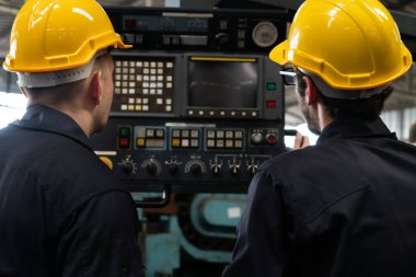 Bir grup yetenekli fabrika işçisi atölyede makine ekipmanı kullanıyor.