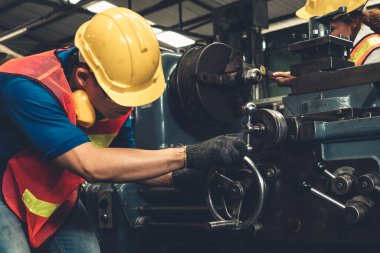 Bir grup yetenekli işçi fabrika atölyesinde makine teçhizatı kullanıyor.