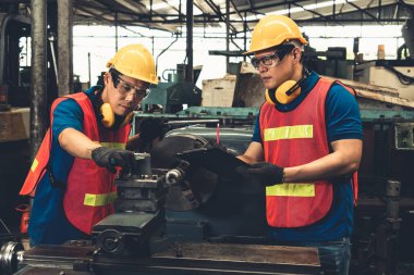 Bir grup yetenekli fabrika işçisi atölyede makine ekipmanı kullanıyor.