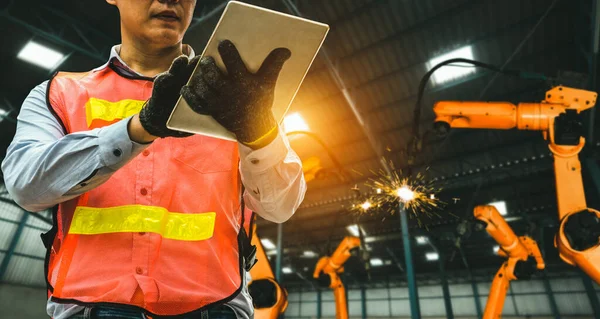 Ingeniero utiliza software robótico avanzado para controlar brazo robot de la industria en fábrica — Foto de Stock