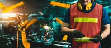 Mühendis fabrikadaki robot kolu kontrol etmek için gelişmiş robotik yazılım kullanıyor.