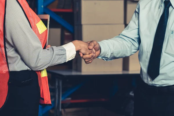 Warehouse worker handshake with manager in storehouse
