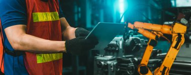 Mühendis fabrikadaki robot kolu kontrol etmek için gelişmiş robotik yazılım kullanıyor.