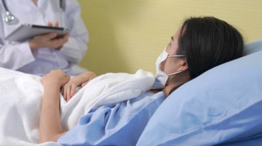 Yüz maskesi takan doktor hastane koğuşundaki hastalarla düzgün bir şekilde konuşuyor.