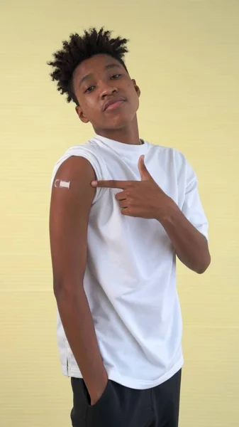Adolescent afro-américain montrant joyeusement le bandage de vaccin COVID-19 — Photo