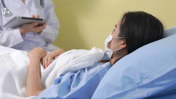 Doctor wearing face mask proficiently talks with patient at hospital ward — Stock Photo, Image