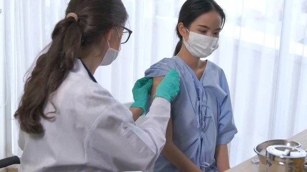 Young woman visits skillful doctor at hospital for vaccination