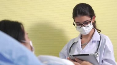 Yüz maskesi takan doktor hastane koğuşundaki hastalarla düzgün bir şekilde konuşuyor.