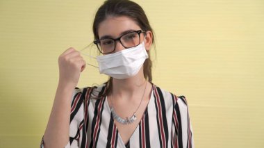 Genç bir kadın yüzünden maskesini çıkarıyor.