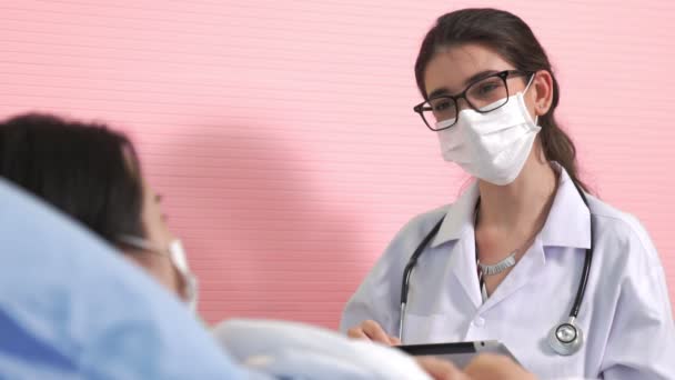 Az arcmaszkot viselő orvos jártasan beszél a beteggel a kórteremben. — Stock videók