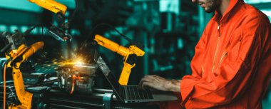 Mühendis fabrikadaki robot kolu kontrol etmek için gelişmiş robotik yazılım kullanıyor.