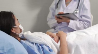 Yüz maskesi takan doktor hastane koğuşundaki hastalarla düzgün bir şekilde konuşuyor.