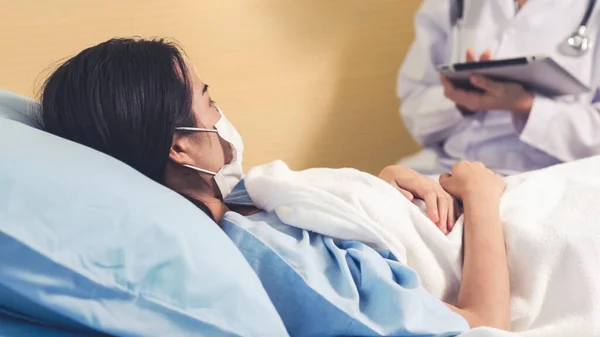 Doctor wearing face mask proficiently talks with patient at hospital ward — Stock Photo, Image