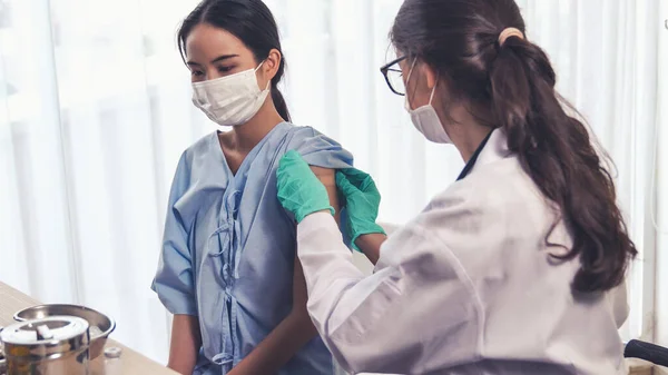 Young woman visits skillful doctor at hospital for vaccination