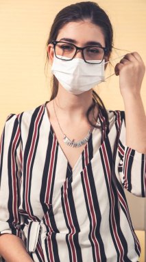 Genç bir kadın yüzünden maskesini çıkarıyor.