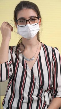 Genç bir kadın yüzünden maskesini çıkarıyor.