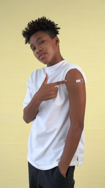 African American teenager showing COVID-19 vaccine bandage merrily — Stock Photo, Image